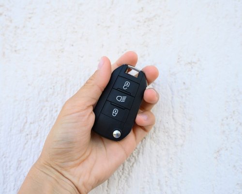 car-key-with-remote-control-in-female-hand-on-whit-3FY5W5B